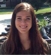 Portrait of person outside with green grass behind them and shadow on their face.