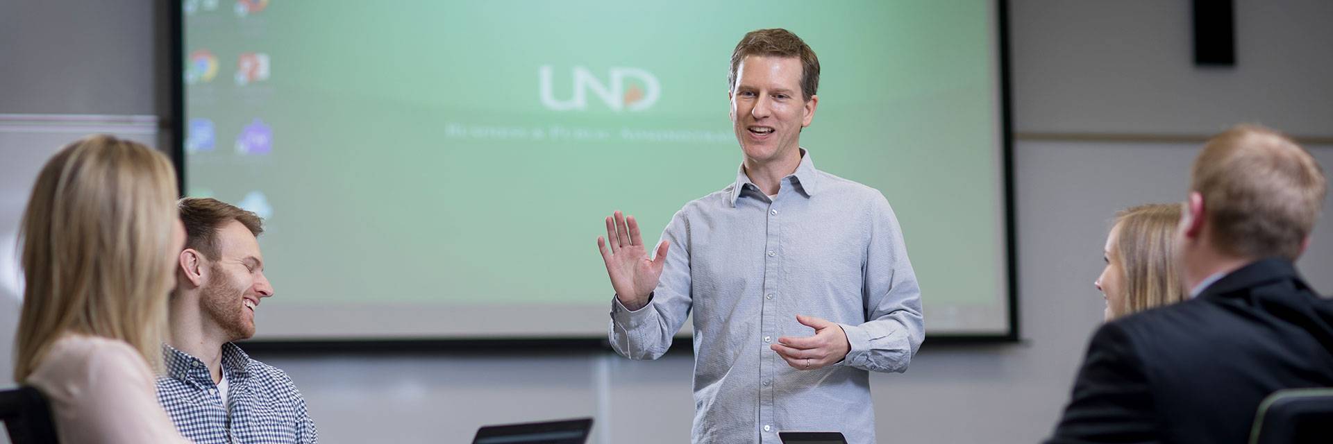 Instructor Goenner stands in front of students, presenting information