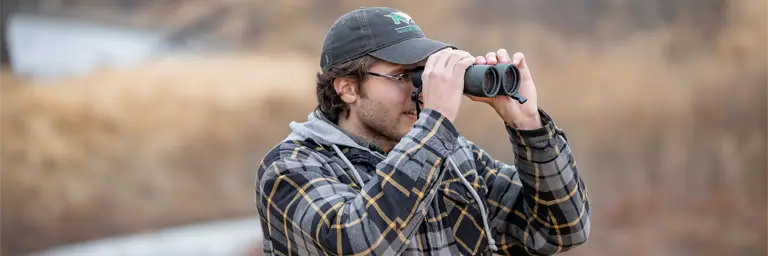 UND Male Biology Student Outside Looking Through Binoculars
