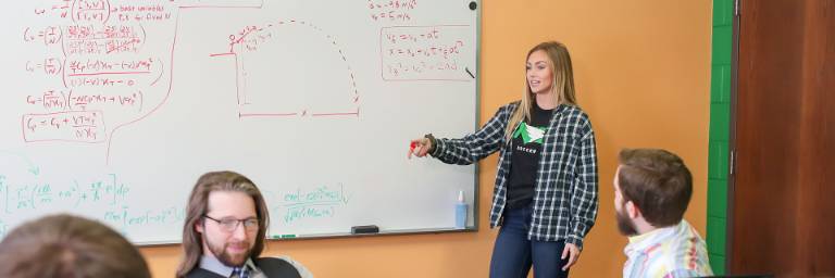Students explaining at whiteboard