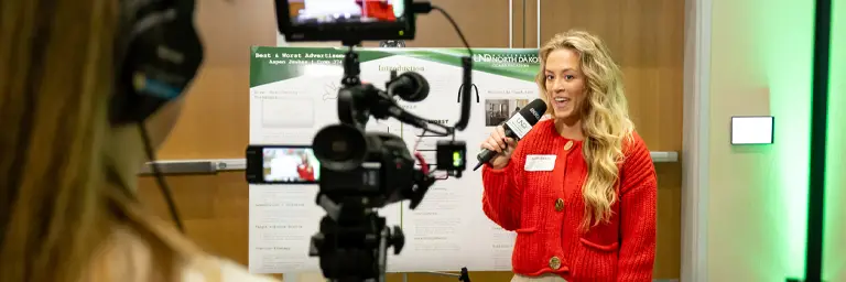 Student with Microphone in front of Video Camera
