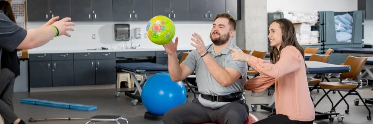 physical therapy students on an exercise ball with instructor