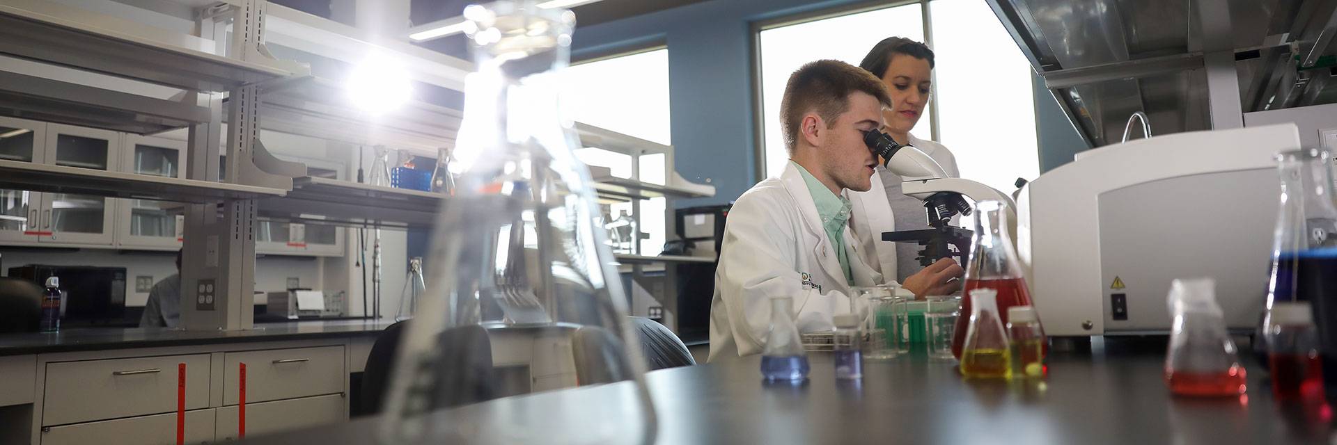 person looking through microscope in medical lab