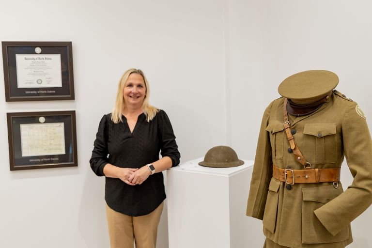 Director standing with military artifacts
