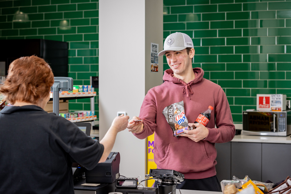 student checking out at a register with snacks in hand