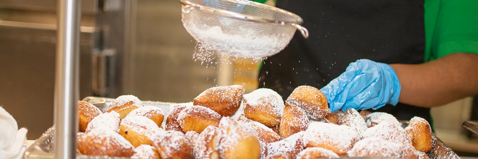 UND Dining Center powdered sugar being sifted onto a pile of fresh beignets.