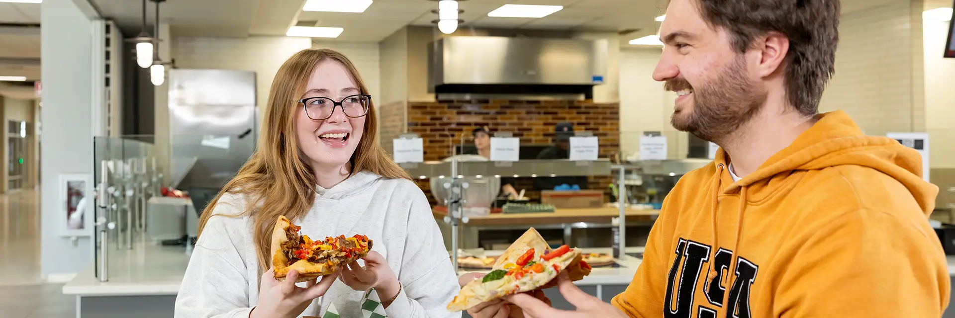 Two students happy enjoy each a slice of pizza