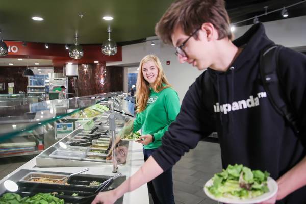 student serving salad from the salad bar