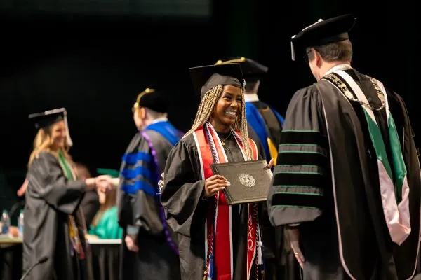 Student smiling with diploma at commencement