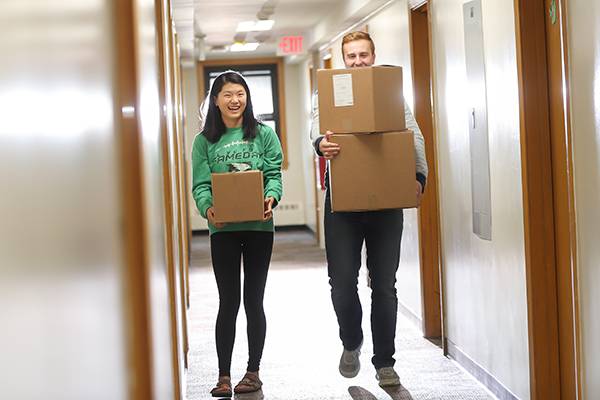 students carrying boxes in hallway