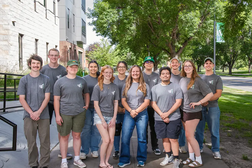 Group of young people pose for a photo with the side walk continuing behind them