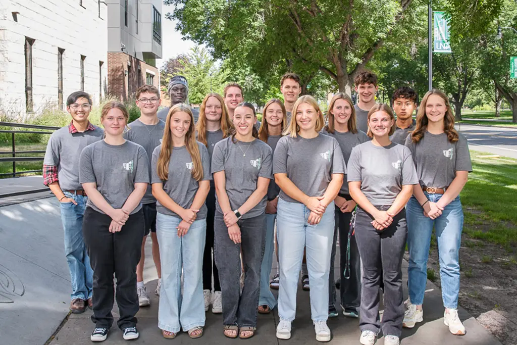 Group of young people pose for a photo with the side walk continuing behind them