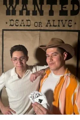 Photo of Castro and Snell holding cards in front of wanted poster decoration