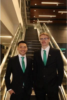 Thingvold and Martin wearing black suits at the bottom of a staircase