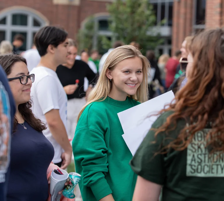 Two students listening at student org member at student org fair