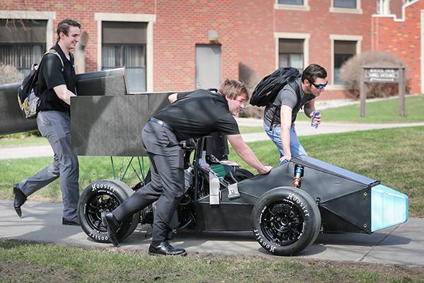 three people moving race car