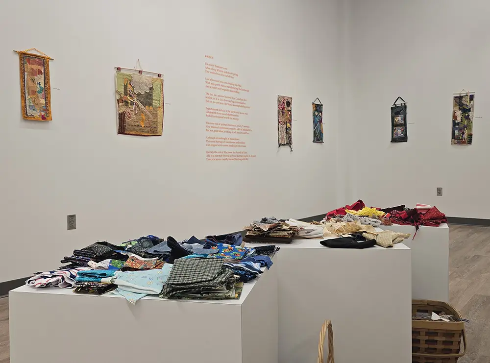 An art gallery featuring cloth displayed on tables and tapestries hanging on the walls.